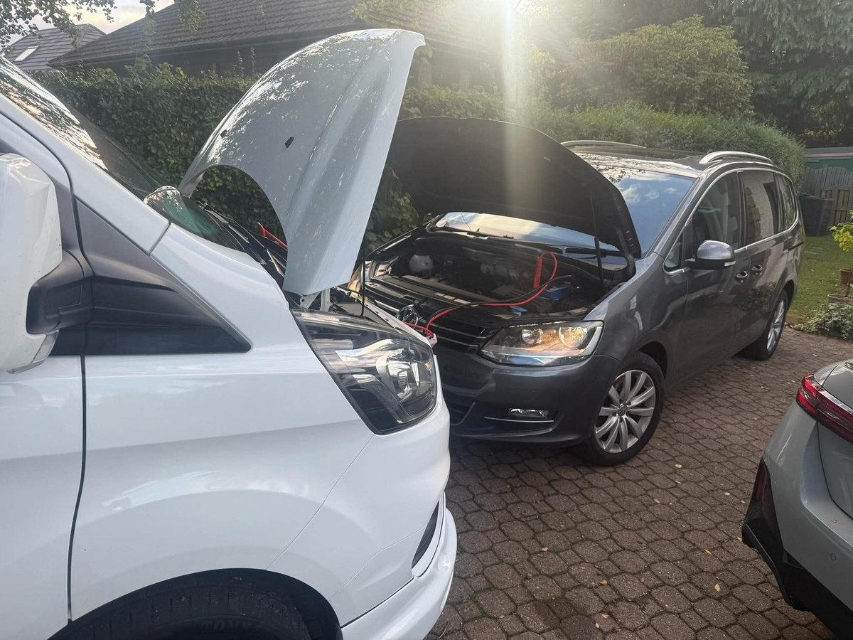 Two cars with open hoods displayed in a driveway for inspection or repair