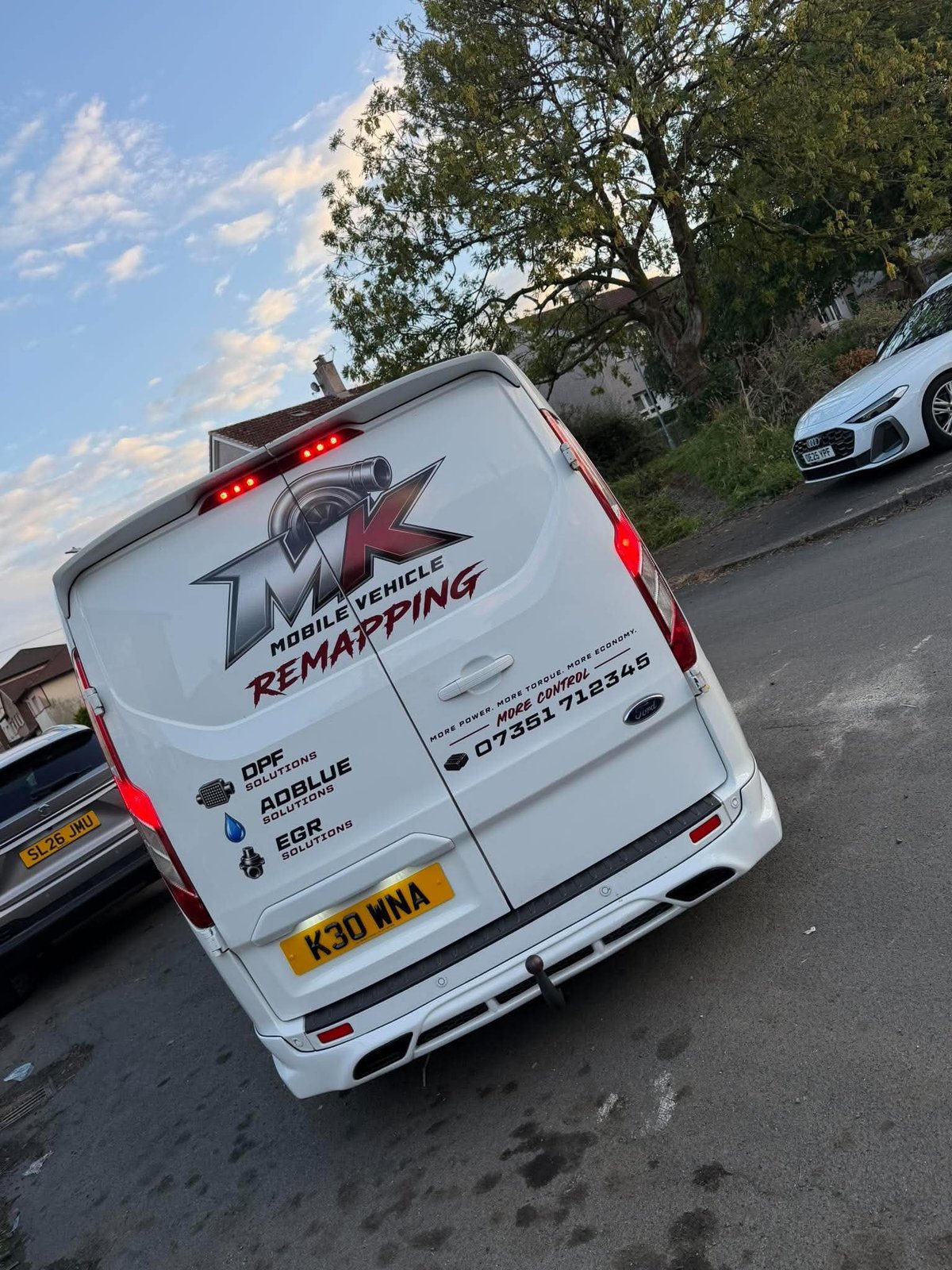 White van with HMI Vehicle Remapping logo parked on a residential street with vehicles and trees in background